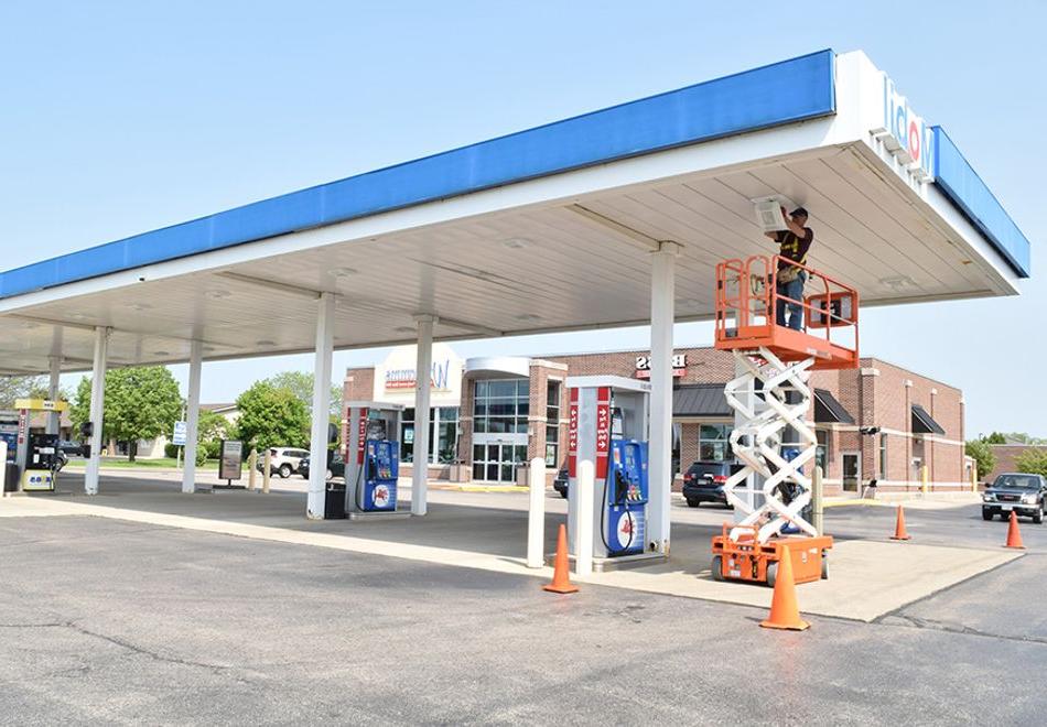 man in a scissor lift at a gas station installing lighting in the canopy covering gas pumps